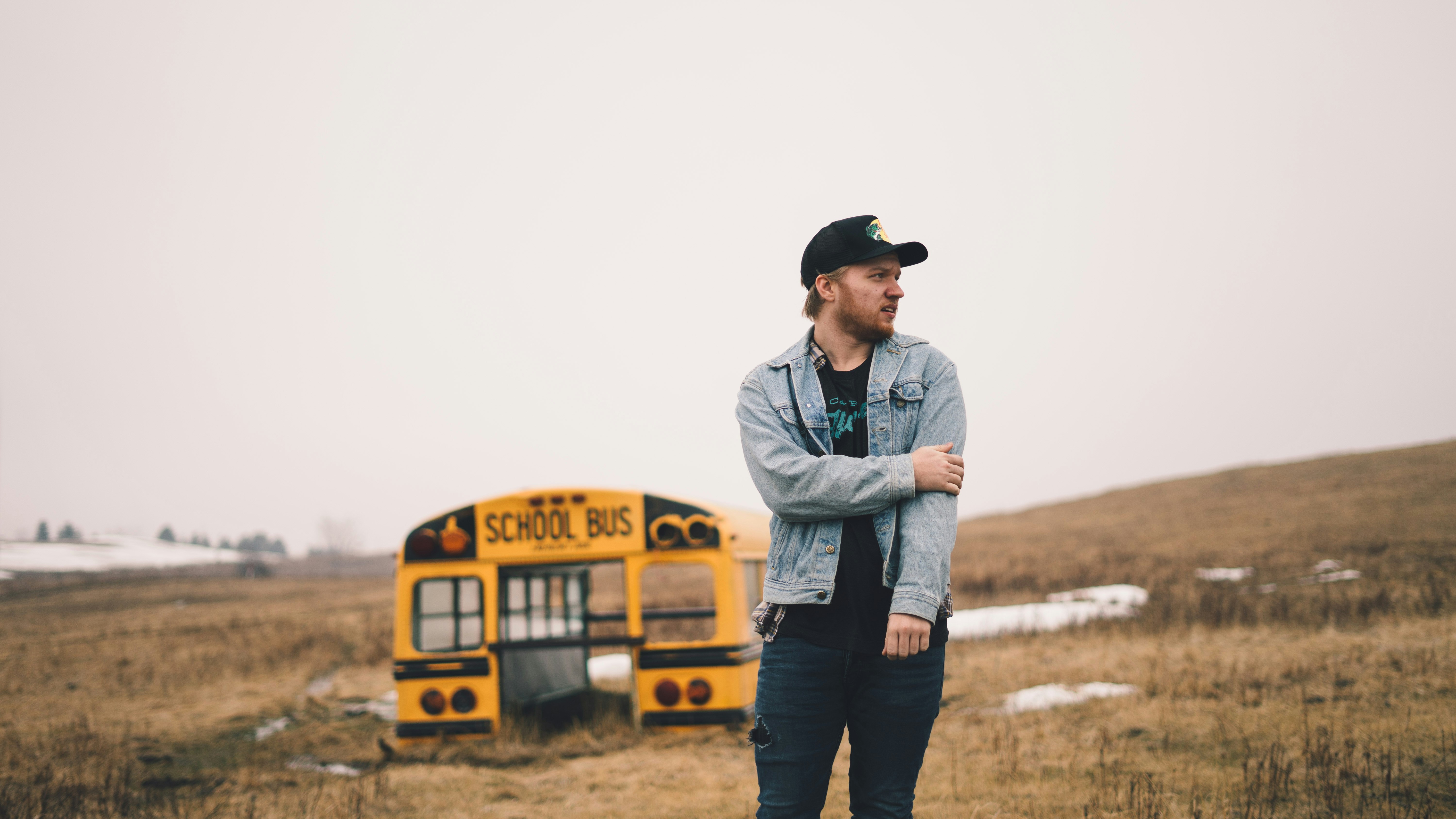 man standing on grass field near school bus part during daytime